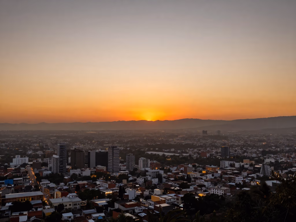 Vista del paisaje desde un mirador en San Joaquín al atardecer, con tonos anaranjados bañando el horizonte.